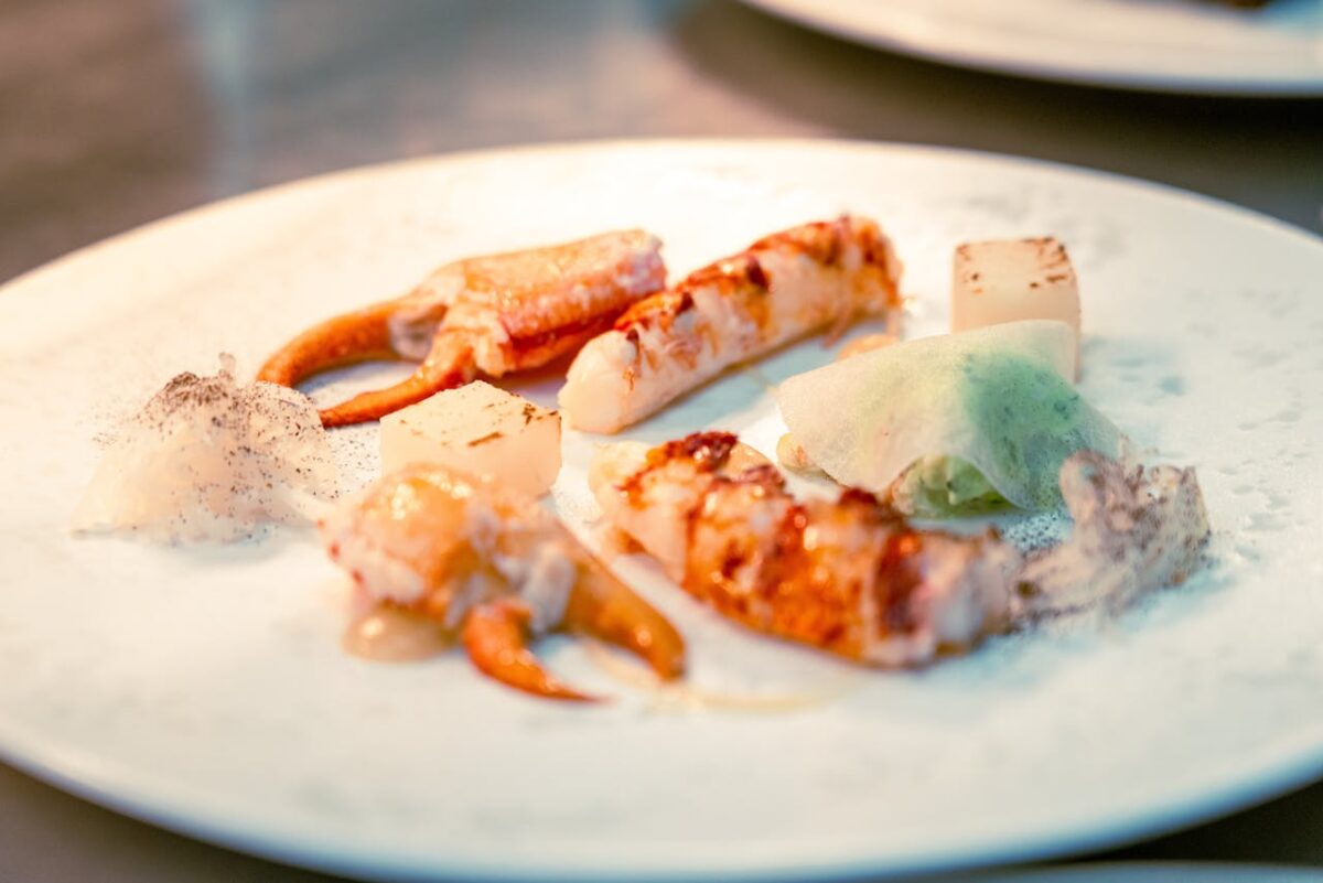 Elegant seafood dish featuring crab claws, lobster, and creative plating, ideal for fine dining contexts.