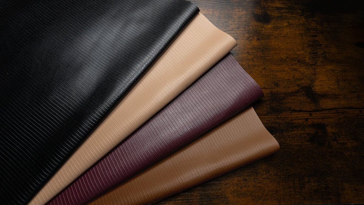 services-02 High-quality textured leather fabrics in various colors on a rustic wooden surface.