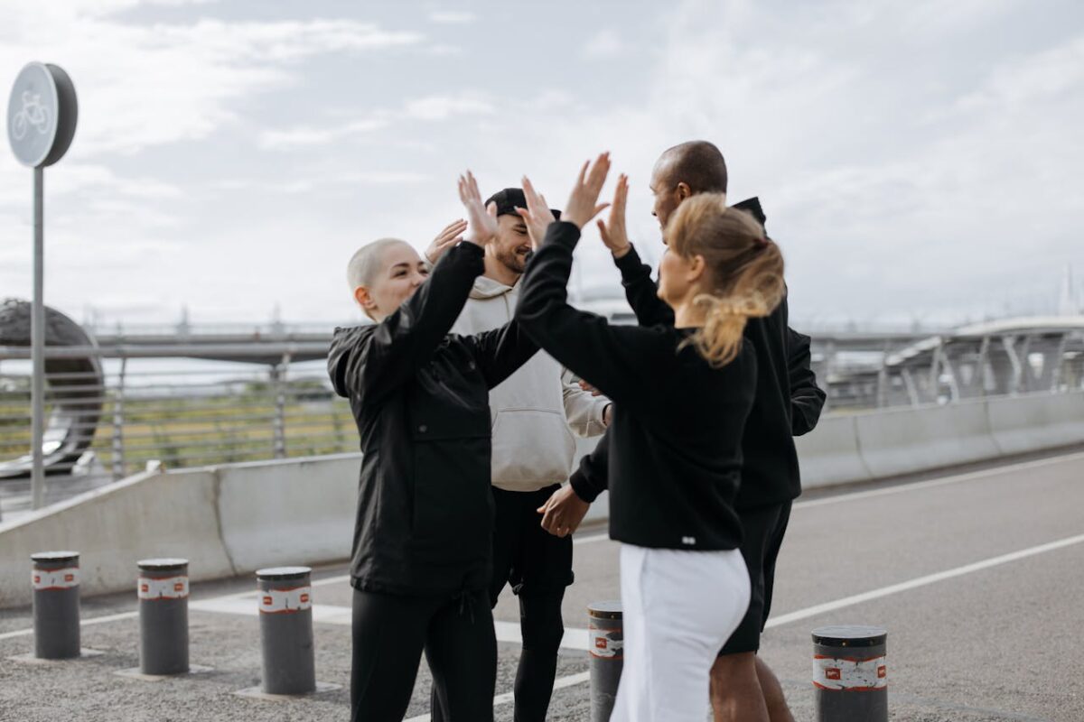 services-01 A diverse group of friends sharing a high five on an outdoor road, symbolizing teamwork and celebration.